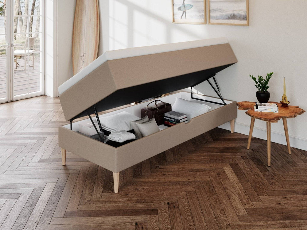 Brun boxmadras Astrid 80x200 med løftbar top, stofbetræk og træben, opbevaring med dyne, pudebetræk og kuffert indeni