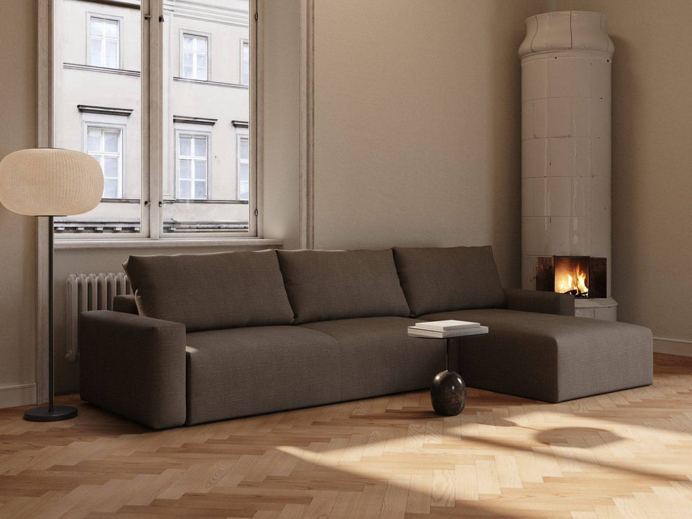 Sovesofa Maru i skovbrun, lav profil med tre løse rygpuder og chaiselong, stofmateriale, placeret i lys stue ved vindue og