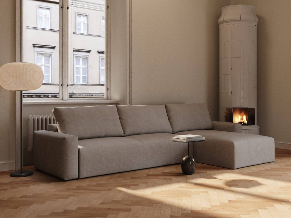 Lysebrun sovesofa i stof (Maru 145x342 cm) med chaiselong i moderne stue ved vindue og tændt kakkelovn