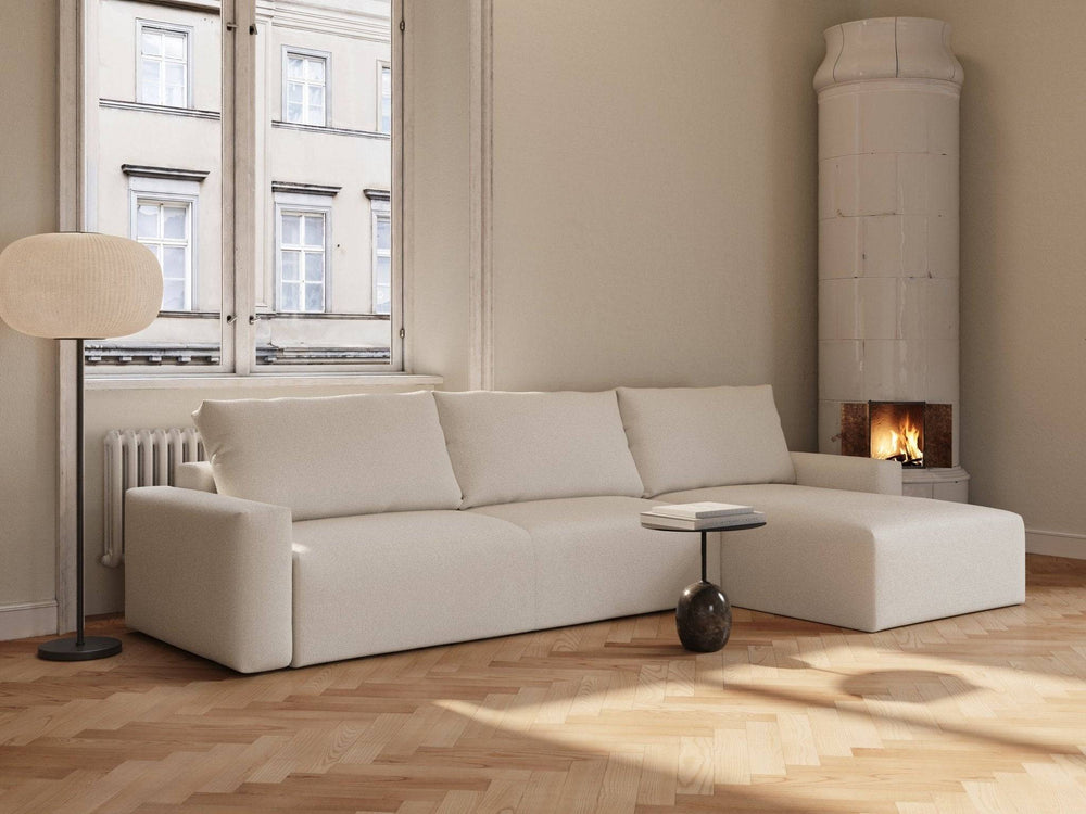 Off-white bouclé sovesofa med chaiselong, bløde puder og lavt armlæn i lyst, minimalistisk rum.