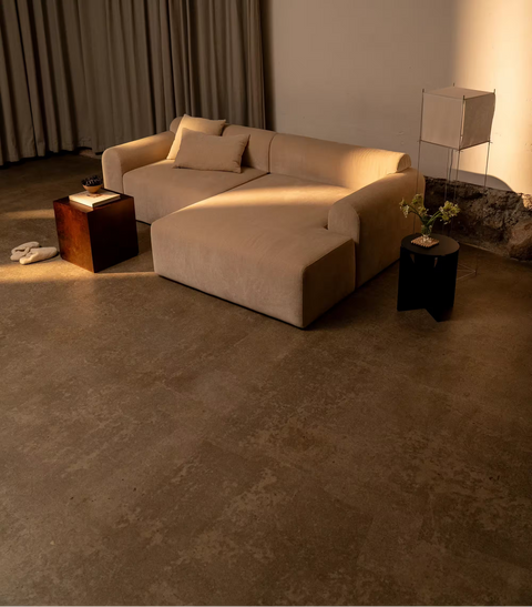 Beige modulsofa i blødt stof med to matchende puder, træsidebord og dæmpet stemningslys.