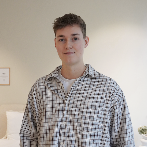 ung person iført ternet bomuldsskjorte i beige, sort og hvid, tæt crop over bryst og ansigt, neutral baggrund