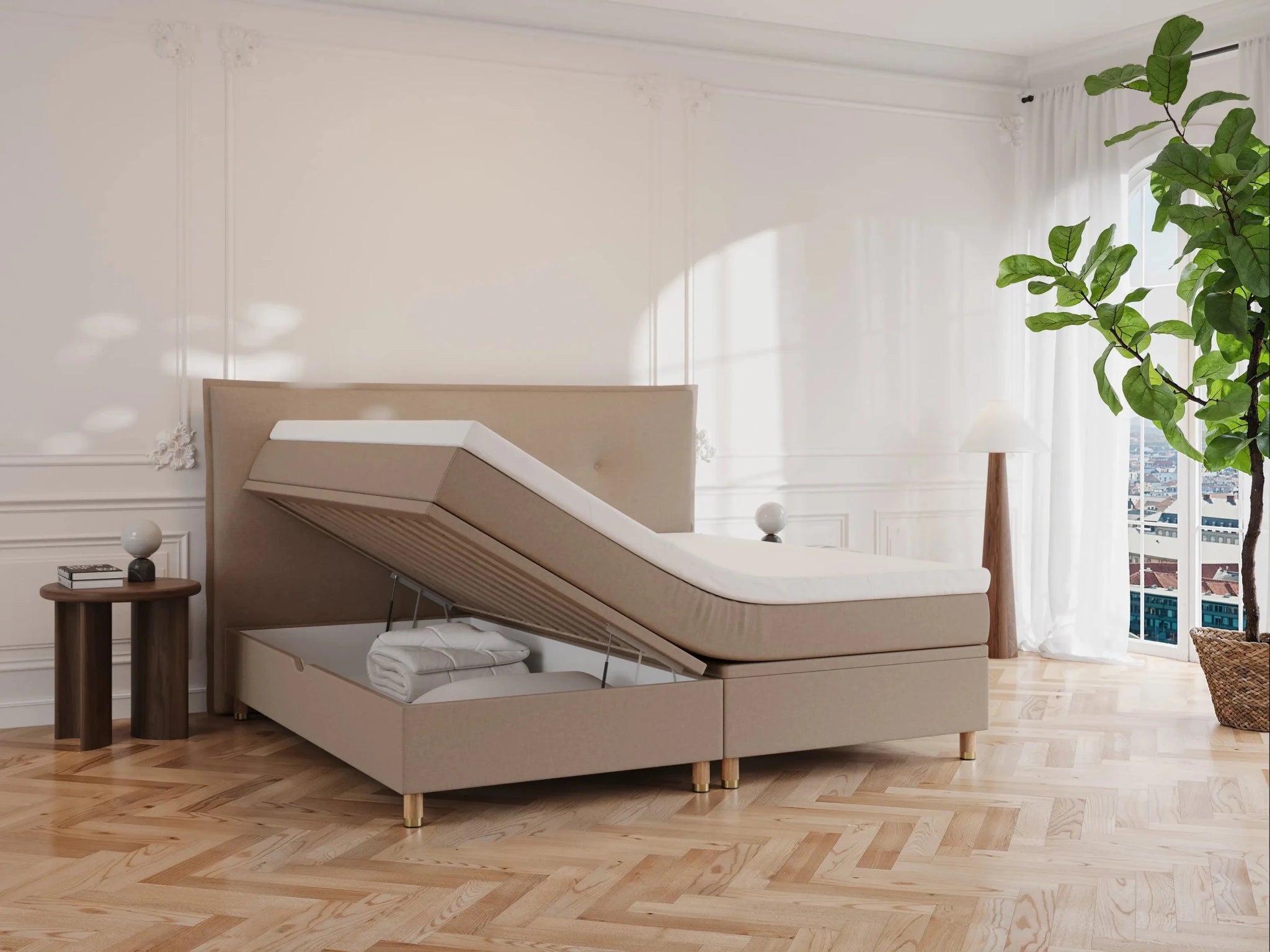 Brun kontinentalseng Alva 200x200 med løftbar topmadras og opbevaringsrum, beige stof, træben, lyse trægulv og planter.