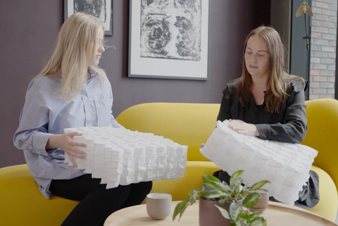 To personer sidder på gul sofa og holder hvide pocketfjedre moduler med quiltet stofoverflade.