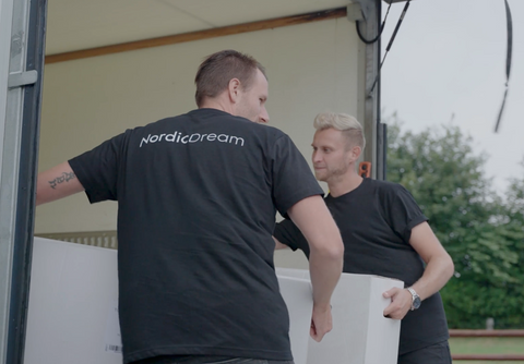 To personer i sorte NordicDream T-shirts løfter hvidt pakket produkt, udendørs, enkel komposition, kontrast sort-hvid