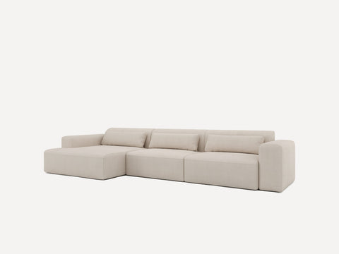 Lysebeige modulsofa med bløde, afrundede kanter og tre rygpuder i bouclé-lignende stof.