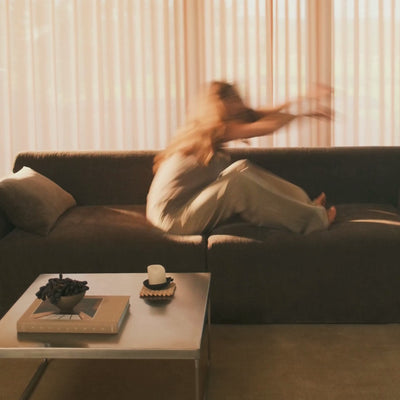 Beige sofa med puder og sløret motiv af en person, varm glød og bløde tekstiler i stuen